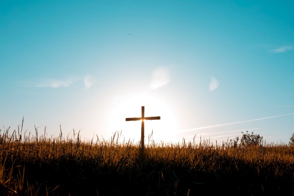 a cross standing in a field on a sunny day